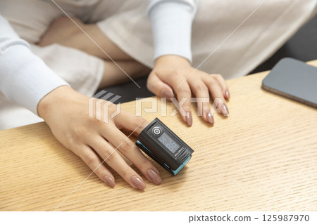 Pulse oximeter on womans left hand. Oxygen level and pulse measuring. 125987970
