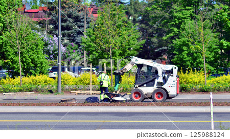 Warsaw, Poland. 26 April 2025. Roadworks and process of asphalting. Blacktopping and paving new road layer. Street construction site and vehicle working in Modlinska street. 125988124