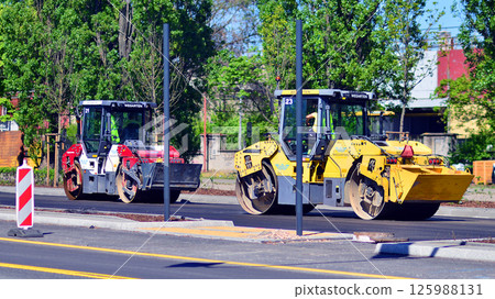 Warsaw, Poland. 26 April 2025. Roadworks and process of asphalting. Blacktopping and paving new road layer. Street construction site and vehicle working in Modlinska street. 125988131
