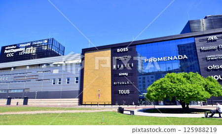 Warsaw, Poland. 1 May 2025. The front wall and the entrance door to the modern shopping center known as the Promenada in sunny day. Warsaw, Poland. 1 May 2025. The front wall and the entrance door to the modern shopping center known as the Promenada in sunny day. 125988219