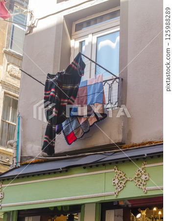 Blankets and towels are hanging on balcony railing drying in sunlight with urban view. High quality photo 125988289