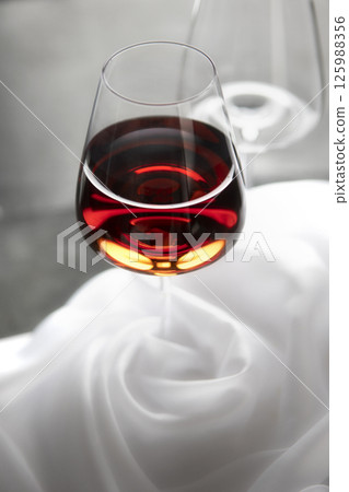 Red wine glass on white cloth background. Neutral background. 125988356