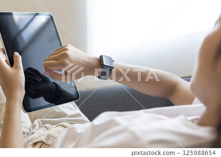 Smiling lady using digital tablet pc browsing internet chilling sitting on couch at home on weekend. Selective focus 125988654
