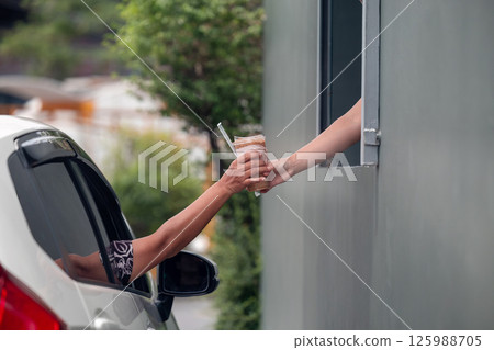 Hand Man in car receiving coffee in drive thru fast food restaurant.  125988705