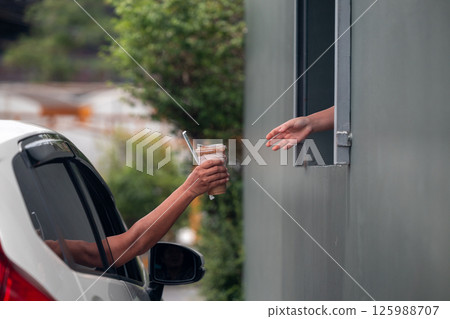 Hand Man in car receiving coffee in drive thru fast food restaurant. Hand Man in car receiving coffee in drive thru fast food restaurant. 125988707