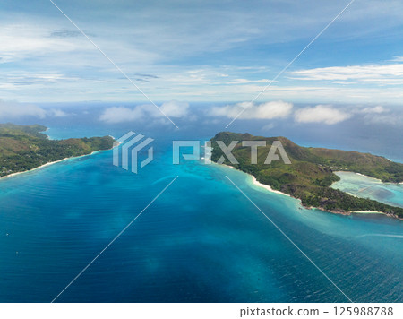 Turquoise bay nestled between two lush green hills, leading out into the vast ocean. Praslin, Seychelles. Turquoise bay nestled between two lush green hills, leading out into the vast ocean. Praslin, Seychelles. 125988788