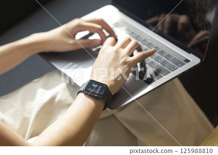 Woman hand with smart watch on wrist, wearable watch and technology computer laptop for communication, checking time. 125988810