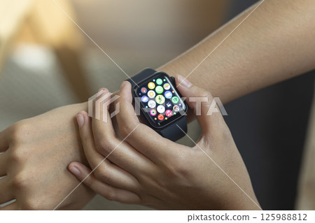 Woman hand with smart watch on wrist, wearable watch and technology computer laptop for communication, checking time. 125988812