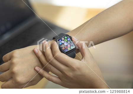 Woman hand with smart watch on wrist, wearable watch and technology computer laptop for communication, checking time. 125988814