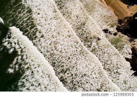 Aerial view Top down Waves crashing on sandy shore,Dark sea surface in summer day background,Seascape top view waves at Phuket Thailand 125989303