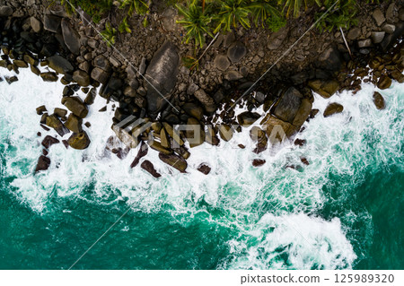 Aerial view Top down seashore, Waves crashing on rocks cliff, Beautiful sea surface in sunny day summer background, Amazing seascape top view seacoast at Phuket Thailand 125989320