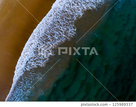 Aerial view Top down Waves crashing on sandy shore,Dark sea surface in summer day background,Seascape top view waves at Phuket Thailand 125989337