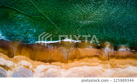 Aerial view Top down Waves crashing on sandy shore,Dark sea surface in summer day background,Seascape top view waves at Phuket Thailand 125989344