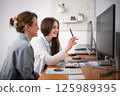 Two businesswomen discuss business planning in the office. 125989395