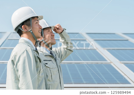 光電發電－身著工作服的電工和技術員站在太陽能板前（清潔能源） 125989494