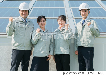 An engineer in work clothes from an electric power company or electrical contractor standing in front of a solar power generation/solar panel (clean energy) 125989649