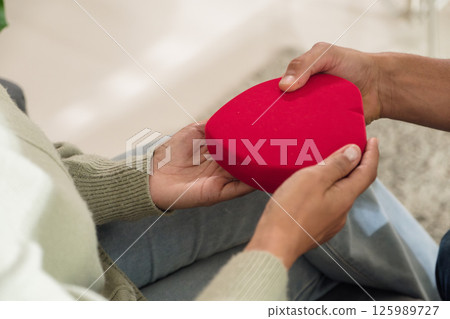 Romantic couple give a surprise gift at home, showing love, relationship, and jewelry in a warm married moment 125989727