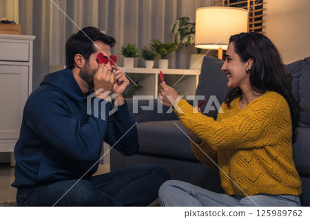 cheerful hispanic couple play with sticker heart together cheerful hispanic couple play with sticker heart together 125989762