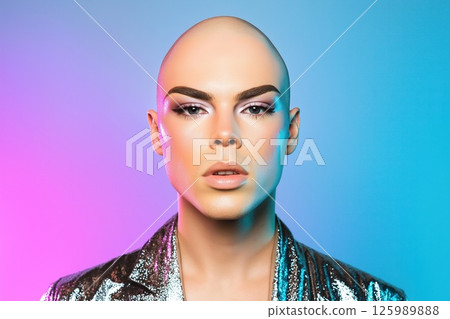 Bald model posing with shiny jacket and colorful makeup in studio 125989888