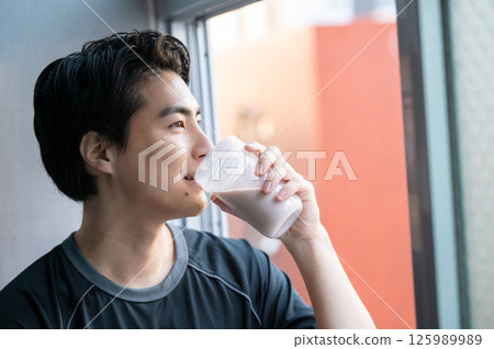 Japanese man drinking protein at the gym Japanese man drinking protein at the gym 125989989