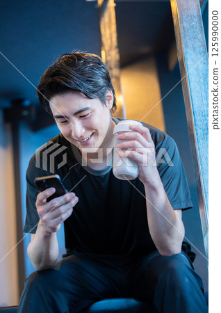 A Japanese man operating a smartphone at the gym 125990000