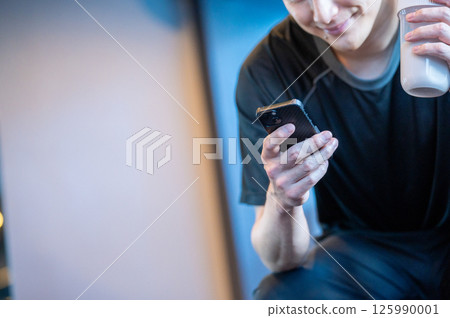 A Japanese man operating a smartphone at the gym 125990001