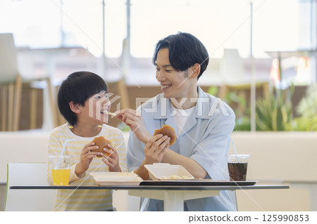 一名 9 歲男孩和他 30 多歲的父親在美食廣場吃飯 125990853