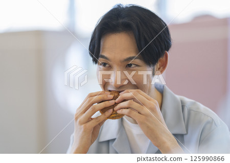 Young man eating hamburger 125990866