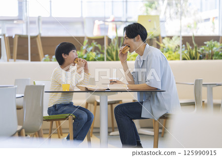 一對父母和孩子麵對面吃漢堡：一個 9 歲的男孩和他 30 多歲的父親 125990915