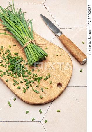 Freshly cut chives on wooden cutting board with knife 125990922