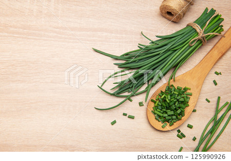 Freshly cut chives resting on wooden spoon and table 125990926