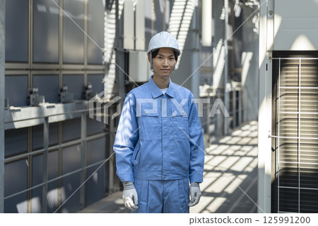A man in his 30s wearing work clothes looking at the camera 125991200