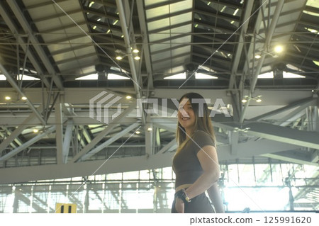 Asian woman smiling while carrying travel bag in airport 125991620