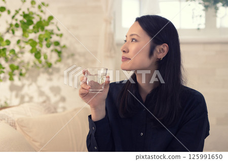 Middle woman drinking water in the living room Middle woman drinking water in the living room 125991650