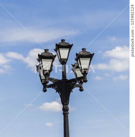 Vintage, cast iron street lamp post with cloudy background Vintage, cast iron street lamp post with cloudy background 125992124