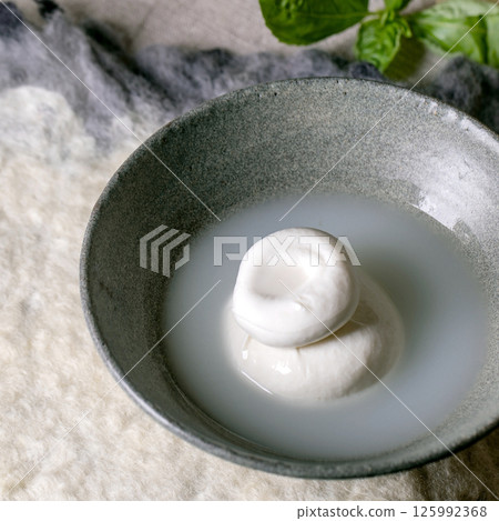 Traditional italian burrata knotted cheese in bowl 125992368