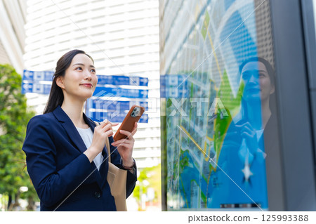 一位女商務人士透過查看地圖和智慧型手機來檢查位置 一位女商務人士透過查看地圖和智慧型手機來檢查位置 125993388