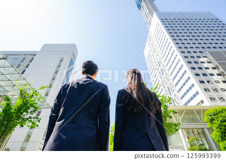 Aerial shot of the backs of a group of business people standing in a city with fresh greenery 125993399