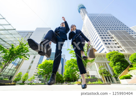 Low angle composition of a group of business people jumping in a city with fresh greenery 125993404