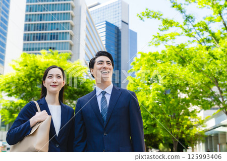An upturned shot of a group of business people standing in a city with fresh greenery An upturned shot of a group of business people standing in a city with fresh greenery 125993406