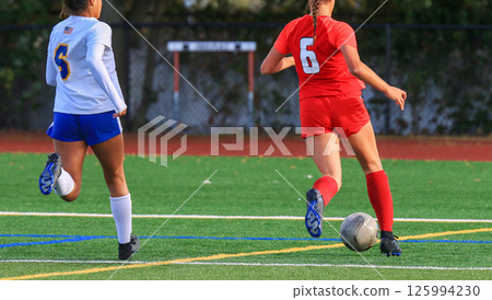 Female Soccer Player Dribbles the Soccer Ball on a Green Field 125994230
