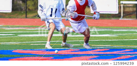 Two Youth Lacrosse Players Competing on a Field During a Game Two Youth Lacrosse Players Competing on a Field During a Game 125994239