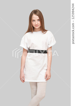 Caucasian young female child in white t-shirt and leggings posing confidently 125994244