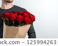 A man holding a bouquet of fresh red roses wrapped in kraft paper on white background, empty space for text. Template of Valentine's Day banner, card, flower delivery, shop advertisements 125994263