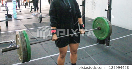 Woman Lifting Heavy Barbell in Gym During Workout Session 125994438