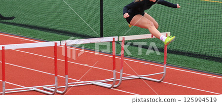 Athlete Clearing Hurdles on Outdoor Track During a Race Athlete Clearing Hurdles on Outdoor Track During a Race 125994519
