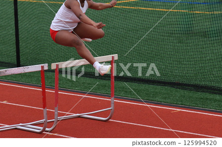Athlete Jumps Over Hurdles During a Track Hurlde Rac3e Athlete Jumps Over Hurdles During a Track Hurlde Rac3e 125994520