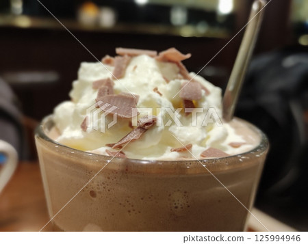 Hot chocolate with cream on top in a transparent glass close view background 125994946