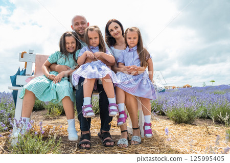 A young family enjoys a moment among purple lavender. A young family enjoys a moment among purple lavender. 125995405