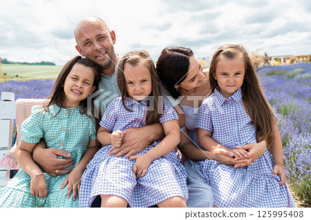 The light-colored dresses of the mother and daughters contrast beautifully with the vibrant purple flowers.  125995408
